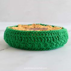 a green crocheted bowl sitting on top of a white counter