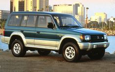 a blue suv parked in front of a body of water