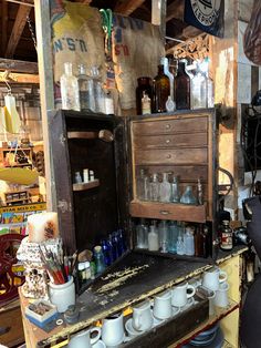 an old wooden cabinet with many bottles and cups on it