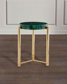 a green marble topped side table with gold legs on hardwood floor next to white wall