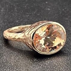 an antique ring with a brown diamond in the center on a black surface, close up