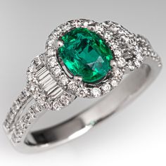 an emerald and diamond ring on a white background