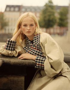 a woman leaning on a wall with her hand on her head and looking at the camera