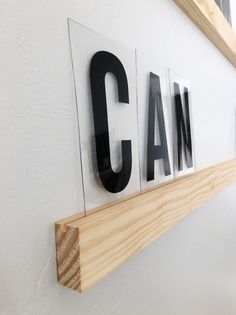 some type of wooden sign hanging on the side of a wall with letters that spell out can