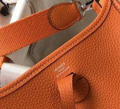 Description HRMS Evelyne 16 Amazone Bag Orange With Silver-Toned Hardware For Women, Shoulder And Crossbody Bags 6.3in/16cm Rep 1:1 Size: 16 x 18 x 5 cm / 6.3 x 7.1 x 2 inches (Length x Height x Width) Since 1978, this bag has enchanted daily riders. First intended to tend horses, it is sewn without a lining and brightened up with an “H” perforation, which the initiates wear against the body, in order to allow the equipment to dry. With its girth-like shoulder strap, the Évelyne is the perfect h Togo Leather, Orange Bag, Orange Leather, Hermes Bags, Shoulder Tote Bag, Shoulder Tote, Luxury Handbags, Enchanted, Real Leather