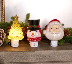 three ceramic christmas decorations sitting on top of a mantle