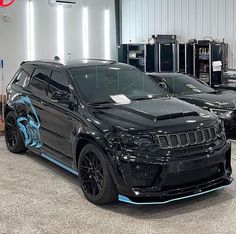 two black cars parked in a garage next to each other with blue accents on them