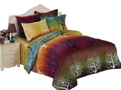 a bed with a colorful comforter and pillows on top of it, next to a night stand