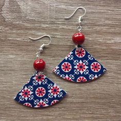 a pair of red, white and blue earrings sitting on top of a wooden table