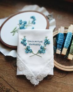 two embroidered handkerchiefs with blue flowers are sitting on a table next to some scissors and thread