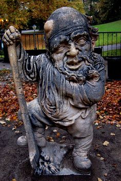 a statue of an old man with a baseball bat in his hand and leaves on the ground around him