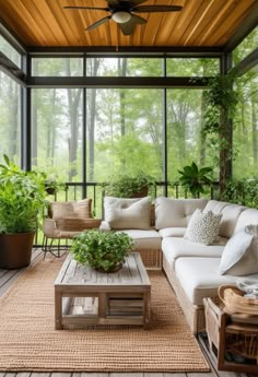 a living room filled with lots of furniture and plants on top of a wooden floor