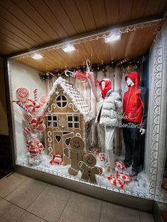 two mannequins dressed in red and white standing next to a gingerbread house