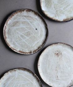 four dirty white plates sitting on top of a metal pan covered in waxed paint