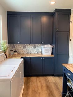 a laundry room with blue cabinets and white washer and dryer on the counter