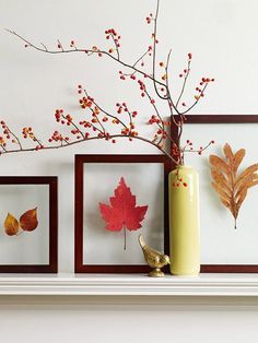 three framed pictures and a vase with autumn leaves on the mantel above it, along with a bird figurine