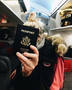 a woman holding up a passport in her hand