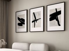 three black and white paintings hang on the wall above a couch in a living room