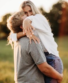 a woman hugging a man in the middle of a field