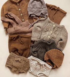 several knitted baby clothes laid out on a white surface