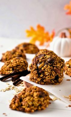 chocolate and oatmeal breakfast cookies on parchment paper with pumpkins in the background