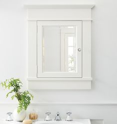 a white sink sitting under a bathroom mirror next to a plant and potted plant