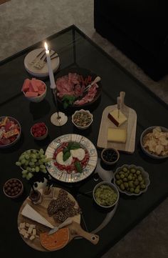 a table topped with plates and bowls filled with different types of food next to a lit candle