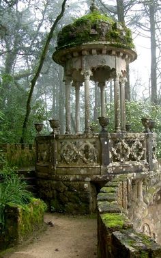 an old stone gazebo with moss growing on it