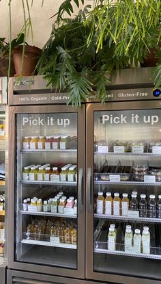 a display case in a store filled with lots of food and drink bottles next to potted plants