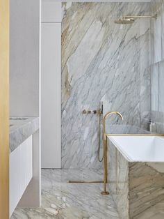 a bathroom with marble walls and flooring next to a bathtub in the corner