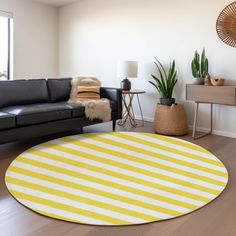 a living room with a black leather couch and yellow striped round rug on the floor