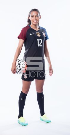 a female soccer player is posing for a photo with her ball and glove in hand