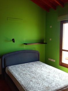 a bedroom with green walls and a white bed in the corner next to a window