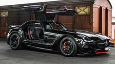 a black sports car parked in front of a train station with its door open and the driver's seat up