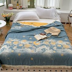 a bed with a blue and yellow blanket on top of it next to a window