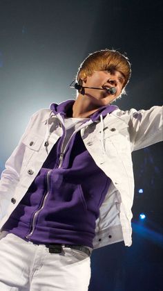 a male in a white jacket and purple shirt is holding his hands out to the side