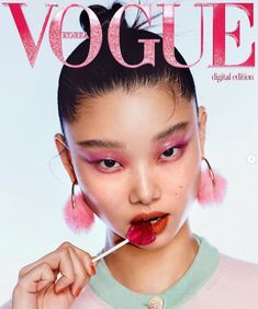 a woman with pink makeup on the cover of a magazine, holding a toothbrush in her mouth