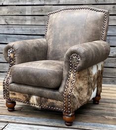 an old chair is upholstered with cowhide and studded trimmings