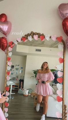 a woman taking a selfie in front of a mirror with hearts on the wall