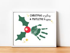 a christmas card with handprints and mistle on the front, in green