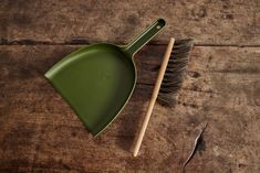 a green dustpan and brush on a wooden surface