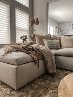 a living room filled with furniture and windows covered in shades of brown, tan and white