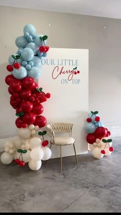 the balloon arch is decorated with cherries and red, white and blue balloons for an anniversary celebration