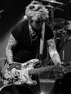 a man with tattoos playing an electric guitar