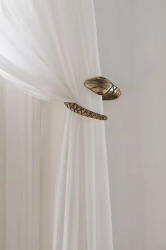 two snakes on the side of a curtain in front of a white wall with sheer drapes