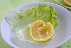 a white plate topped with lettuce and lemon slices