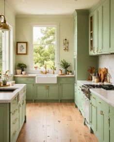 a kitchen filled with lots of green cabinets and white counter tops next to a window