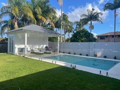 a backyard with a pool, covered patio and palm trees in the backround