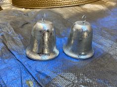 two silver bells sitting on top of a blue sheet