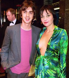 two people standing next to each other in front of a crowd at an event with one woman wearing a green dress